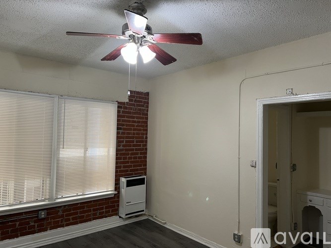 A room with a ceiling fan and a window with blinds.