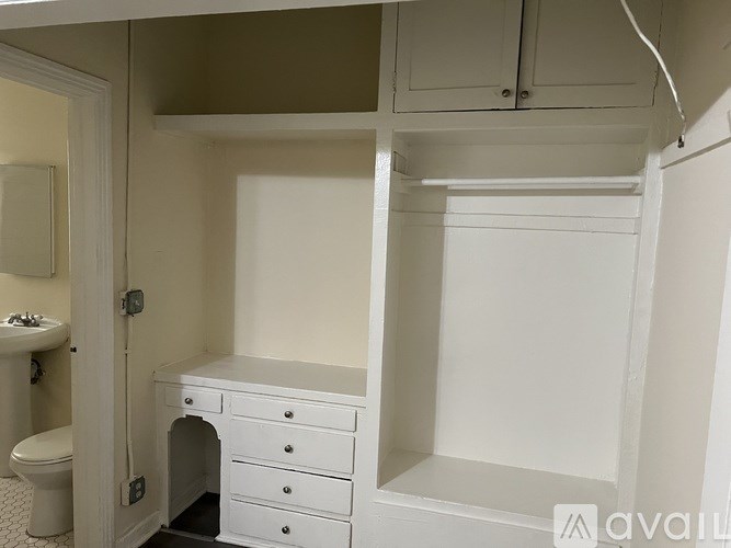 A white bathroom with a toilet, sink, and a desk.