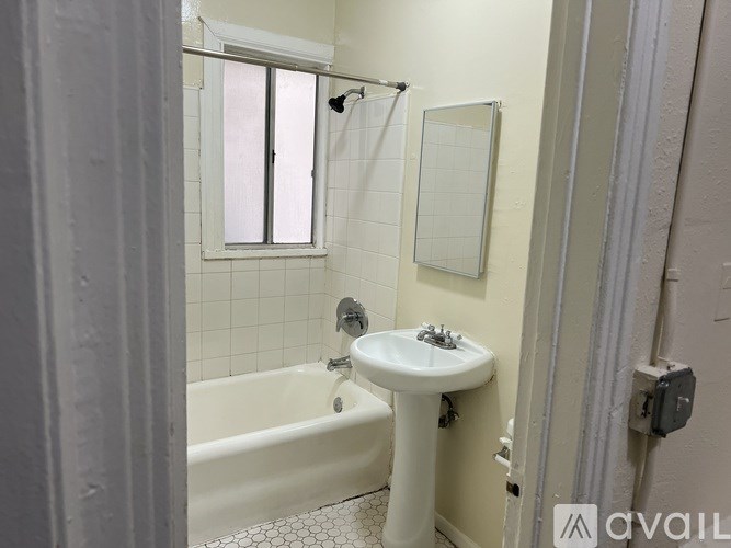 A bathroom with a white tub, sink, and tiled walls.