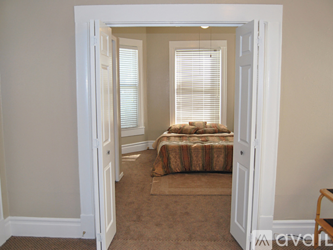 A small bedroom with a bed in the corner and a window with blinds.