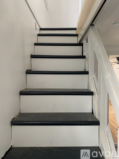 A set of black and white stairs with a wooden handrail.
