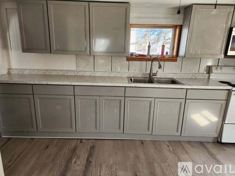 A kitchen with grey cabinets and a window.