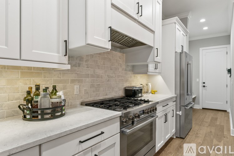 A kitchen with white cabinets and a marble countertop.