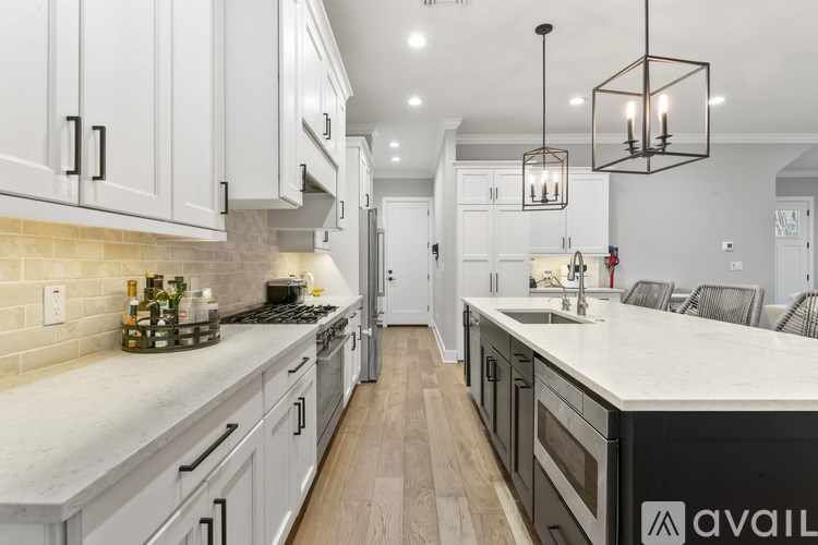 A modern kitchen with white cabinets and a marble countertop.