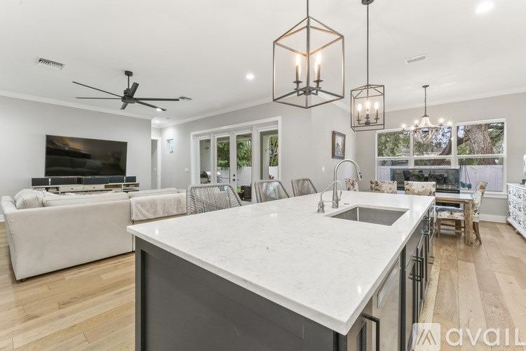 A modern kitchen with a large island and a living room area with a sofa and television.