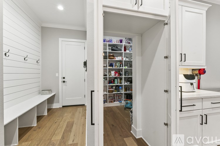 A kitchen with white cabinets and a pantry with a door open.