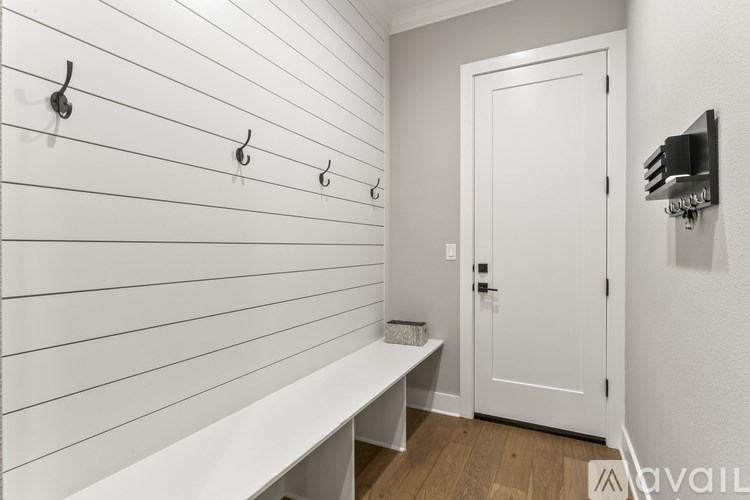 A white bathroom with a white door and a white bench.