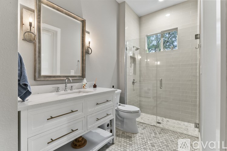 A bathroom with a white sink vanity and a walk-in shower.