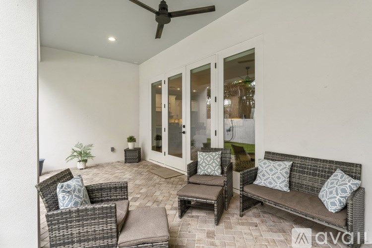 A patio with a couch, chairs, and a ceiling fan.