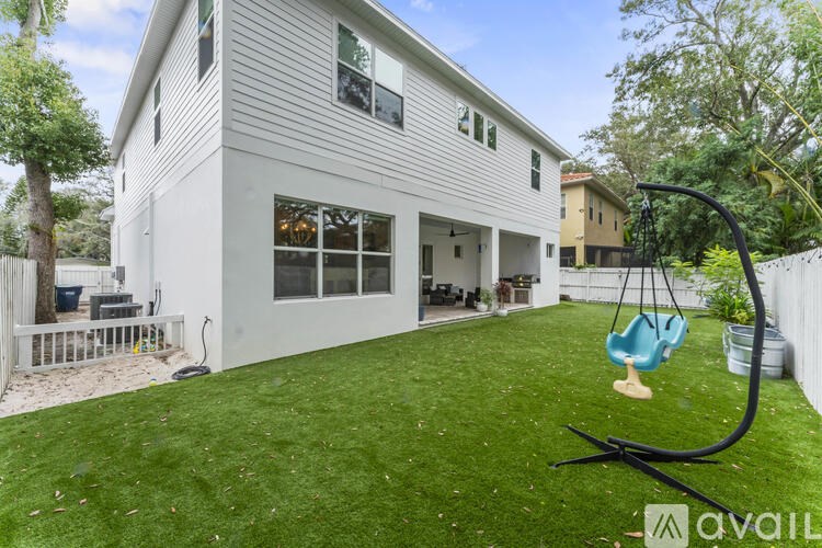 A white house with a swing in the yard.