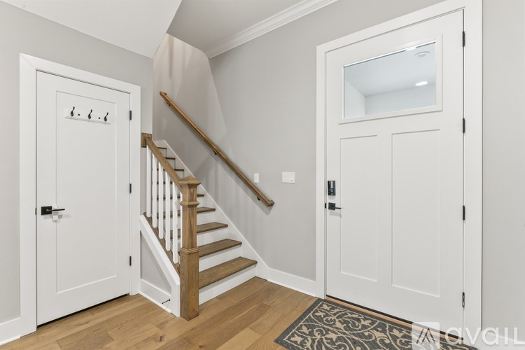 A white door with a black handle is on the left side of a wooden staircase.