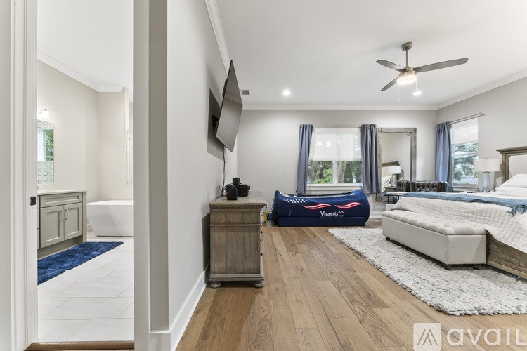 A bedroom with a bed, a dresser, and a ceiling fan.