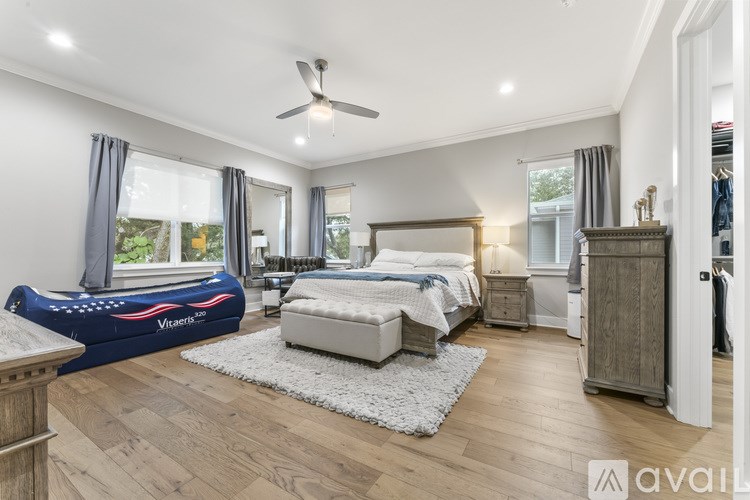 A bedroom with a bed, dresser, and a fan.