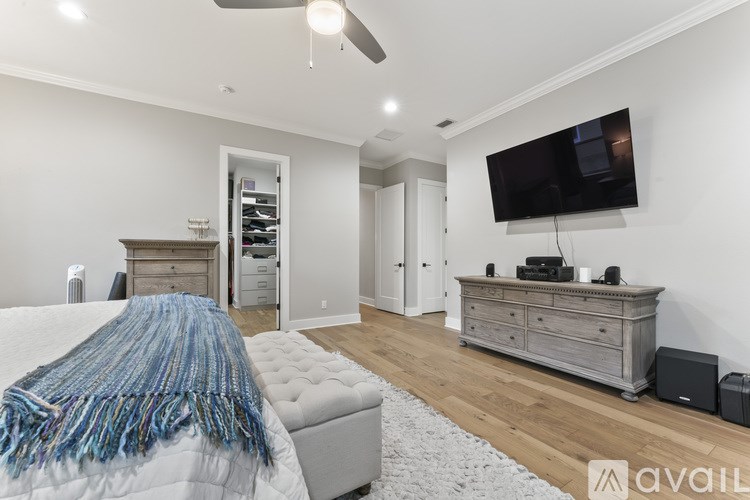 A modern bedroom with a large bed and a flat screen TV mounted on the wall.