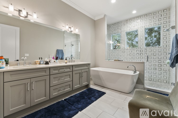 A bathroom with a white bathtub and a large mirror.