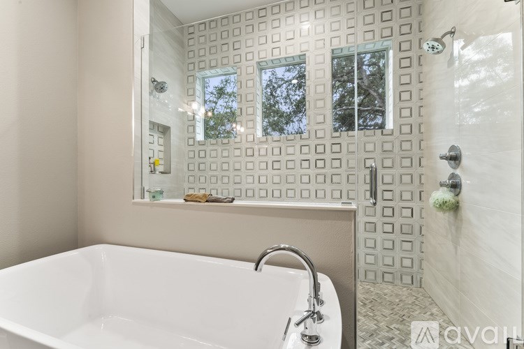 A white bathtub with a shower head and a mirror above it.