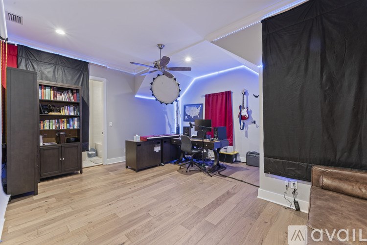 A room with a ceiling fan, a bookshelf, and a guitar.