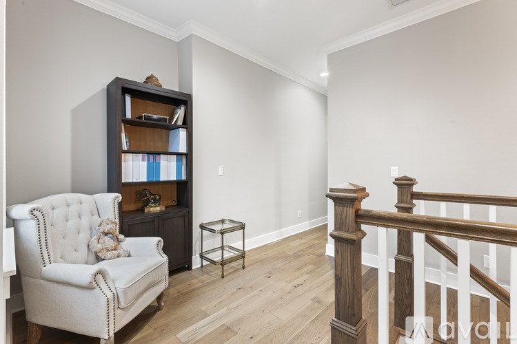 A living room with a white chair, a bookshelf, and a small table.