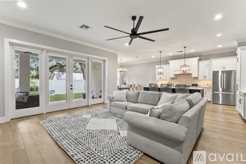 A spacious living room with a grey sofa and a black and white rug.