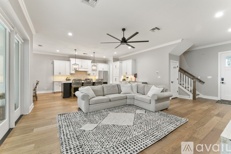 A spacious living room with a white sofa set and a black and white rug.