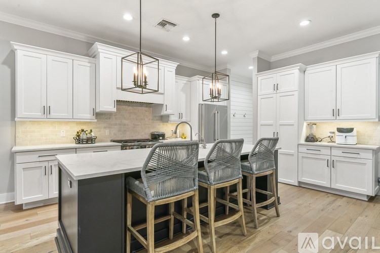 A kitchen with white cabinets and a black island.