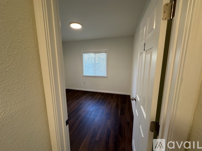 A hallway with a wooden floor and a white door.