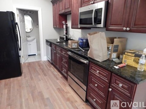 A kitchen with dark wood cabinets and a black refrigerator.