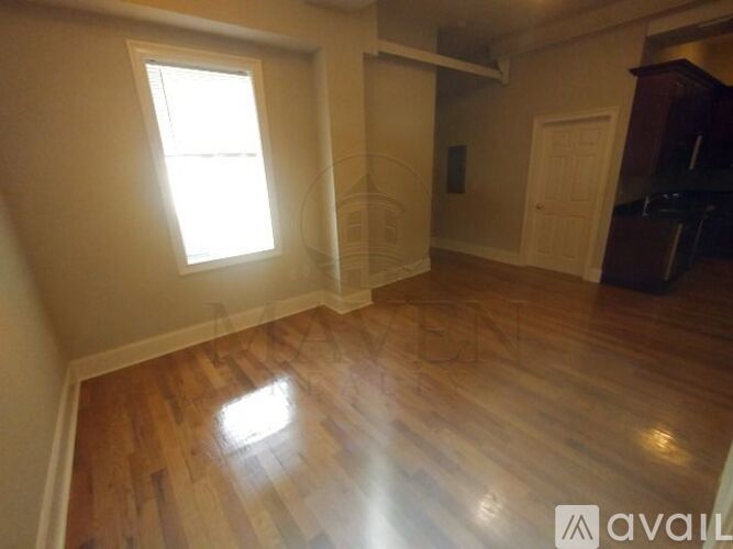 A room with wooden flooring and a window letting in natural light.