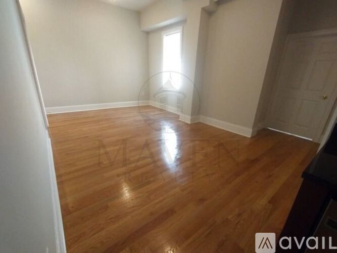 A room with wooden flooring and a window letting in sunlight.