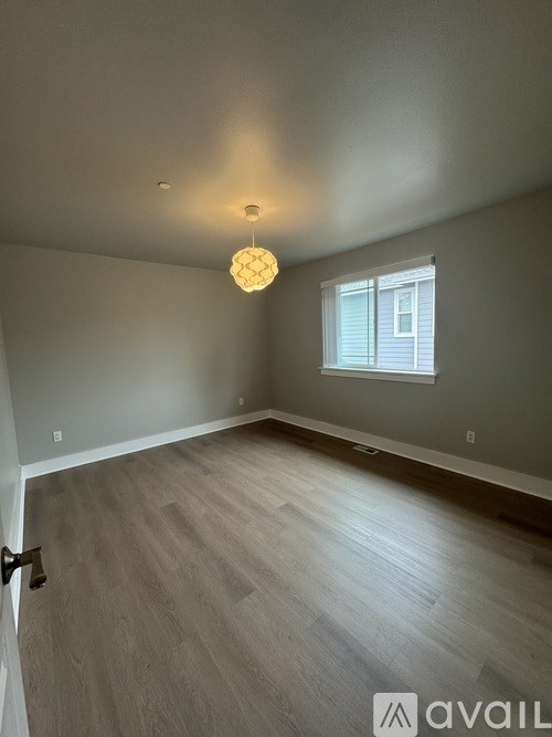 A room with a wooden floor and a window with blinds.