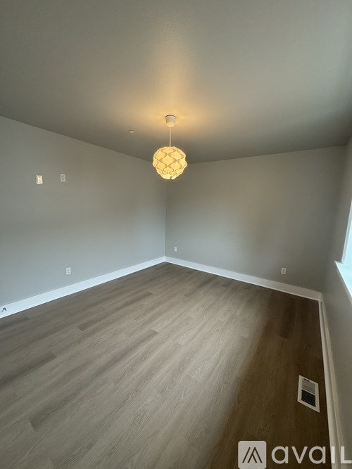 A room with wooden flooring and a light hanging from the ceiling.
