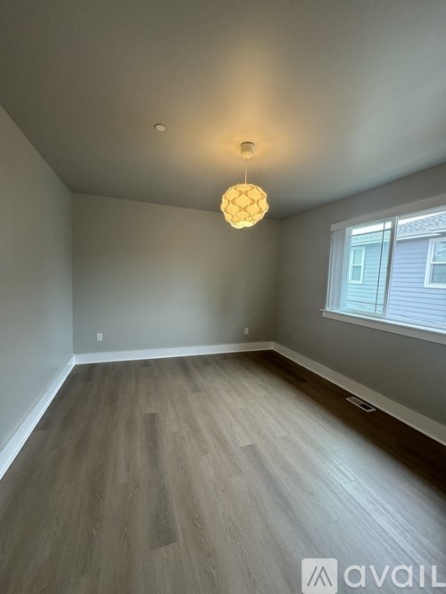 A room with a wooden floor and a hanging light fixture.