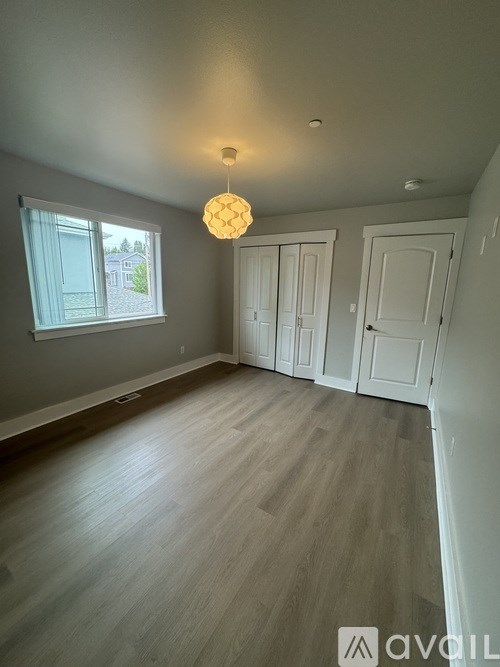 A room with wooden flooring and a hanging light fixture.