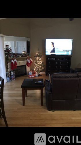 A living room with a fireplace, a chair, a coffee table, and a television playing a movie.
