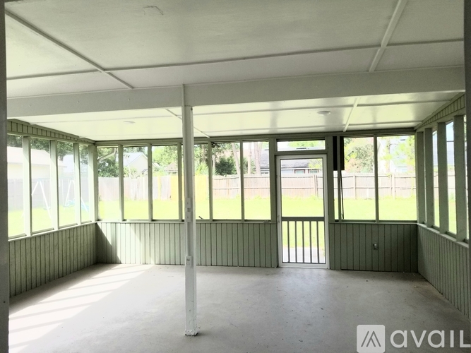 A large empty room with a view of a grassy area outside.