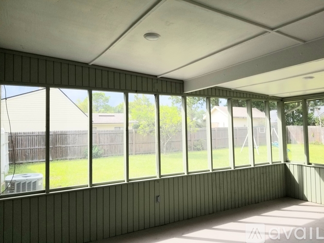 A room with a green wall and a window overlooking a backyard.