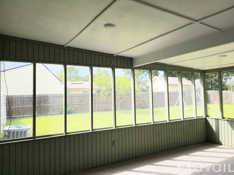 A room with a green wall and a window overlooking a backyard.