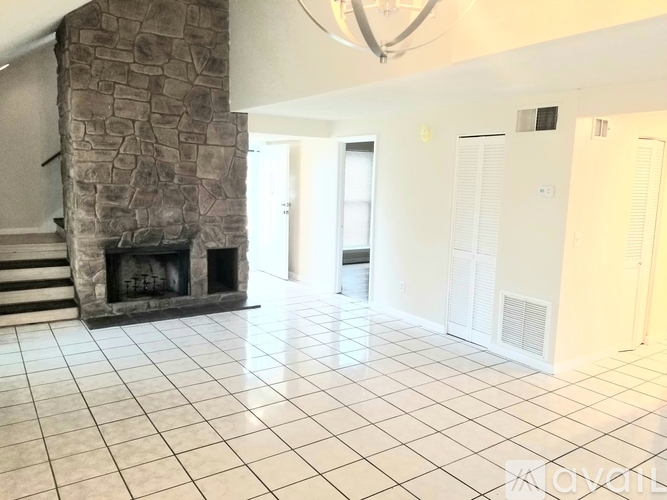 A stone fireplace in a white tiled room.