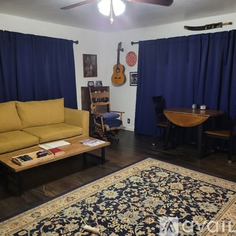 A living room with a yellow sofa and a rug.