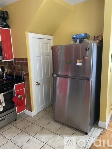 A kitchen with a stainless steel refrigerator and a white door.