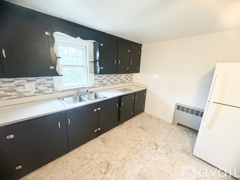 A kitchen with black cabinets and a white fridge.