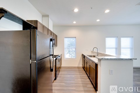 A kitchen with a black refrigerator and wooden floors.