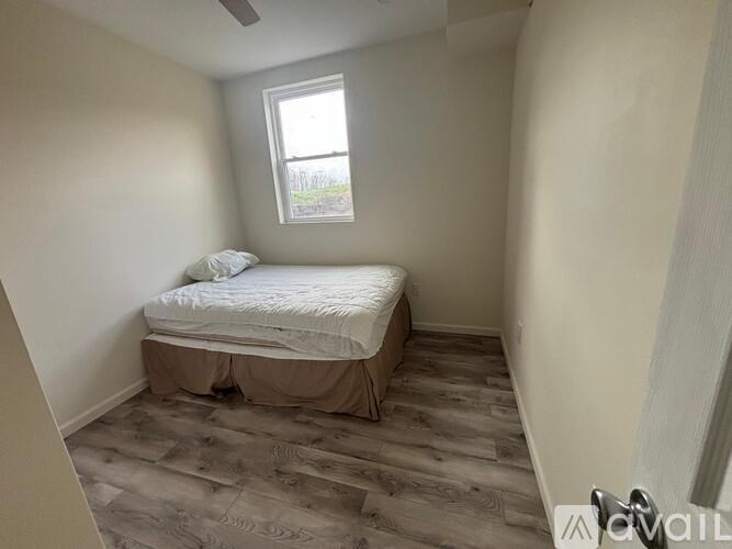 A bedroom with a bed, wooden flooring, and a window.