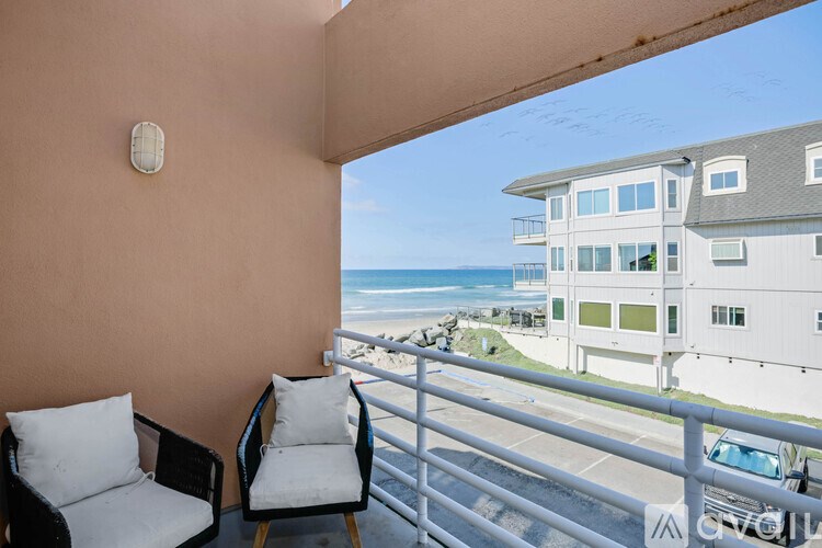 Two chairs are on a balcony overlooking the ocean.