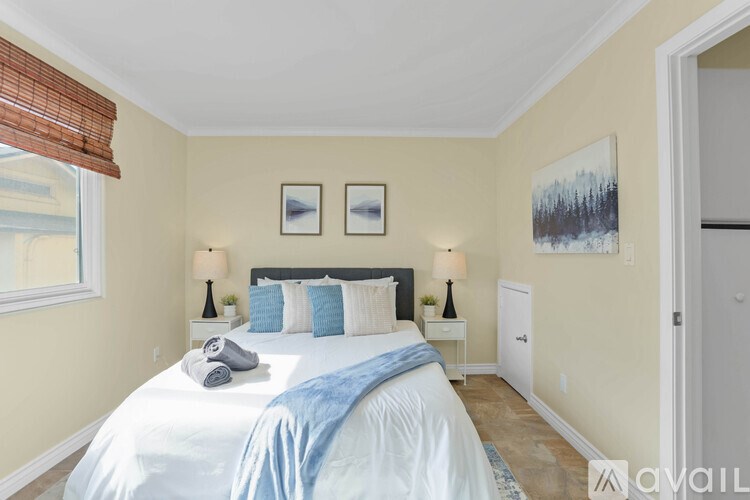 A bedroom with a large bed and two lamps.