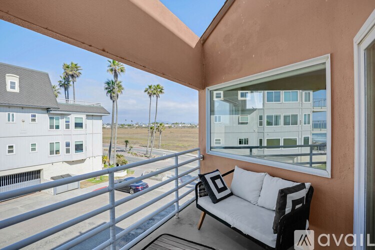 A balcony with a couch and a view of a building and palm trees.