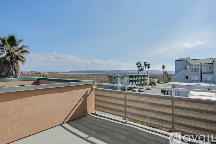 A balcony with a view of the ocean and palm trees.