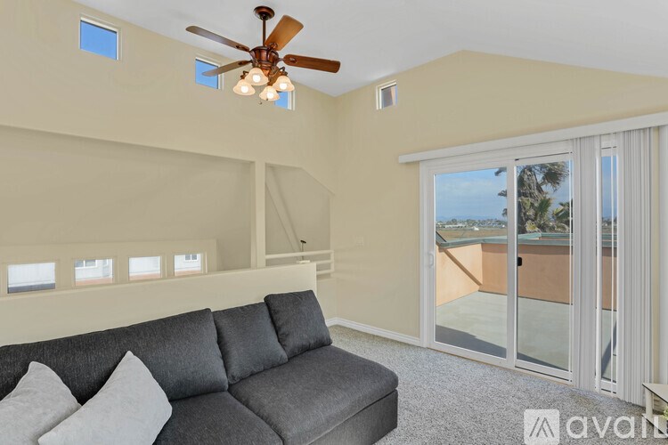 A living room with a grey couch and a ceiling fan.