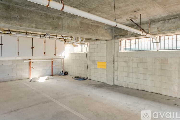 A large empty room with concrete walls and ceiling, and a window on the right side.