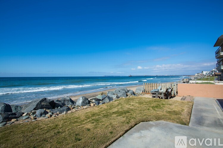 A beachfront property with a clear blue sky and ocean in the background.